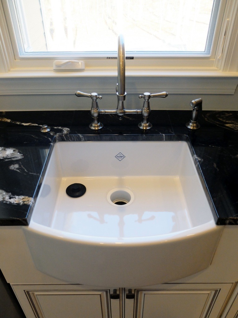 A farmhouse sink with a polished nickel faucet.