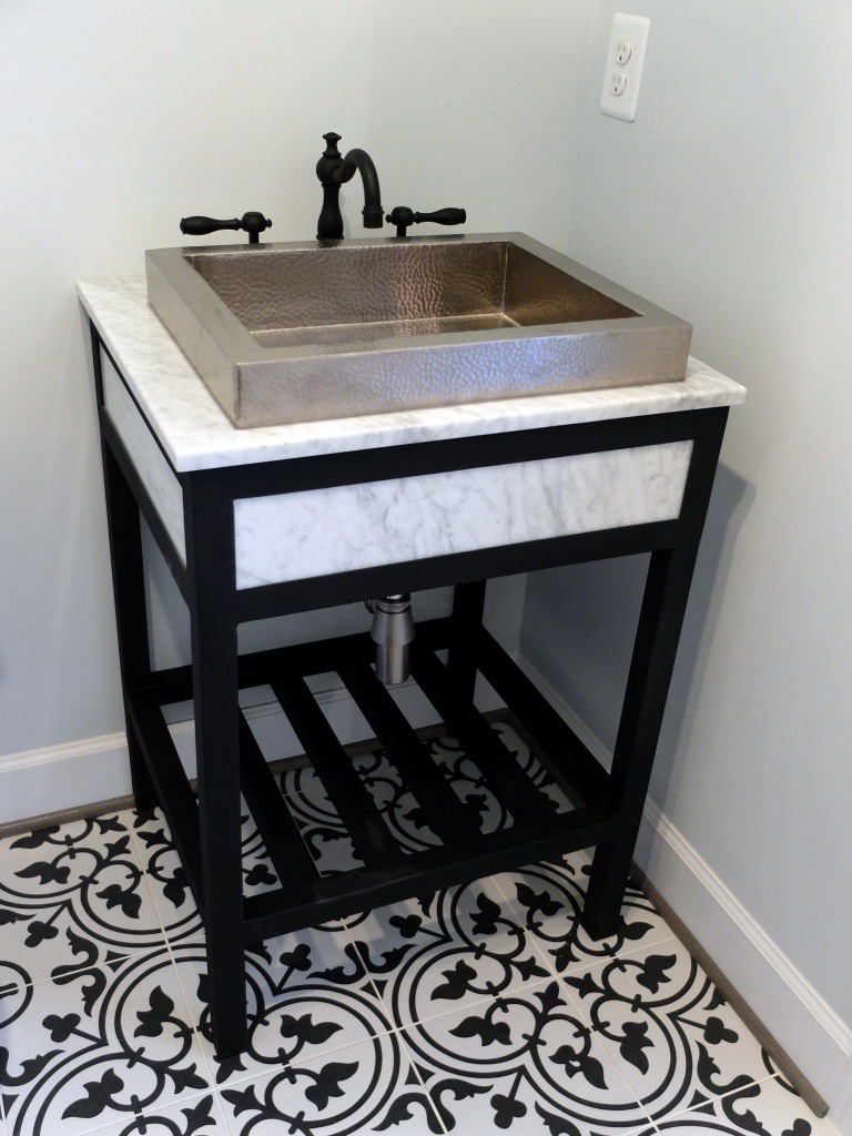 A beaten metal vessel sink with a black faucet.